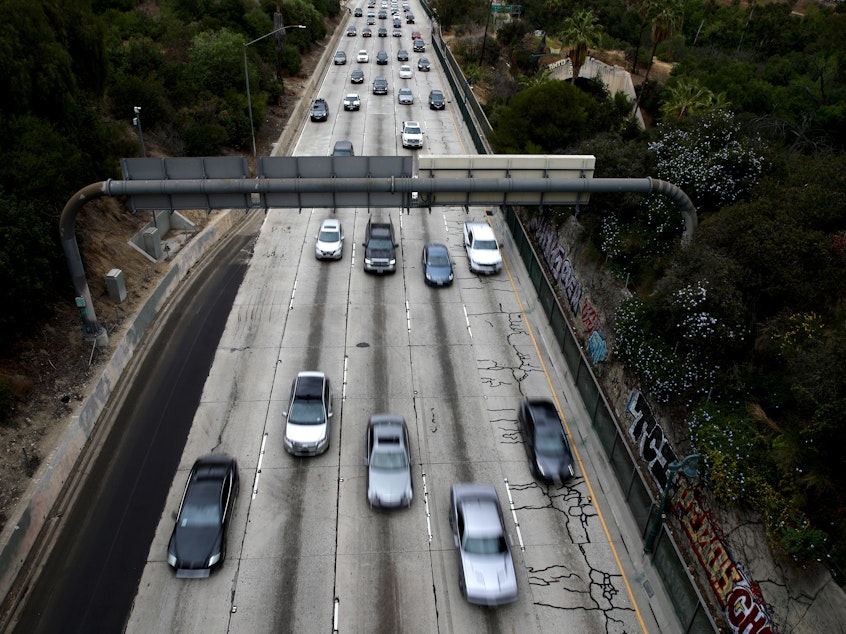 caption: Cars drive down the 110 Freeway toward downtown Los Angeles, California in April 2021. President Biden has pledged to cut U.S. greenhouse gas emissions in half by 2030.