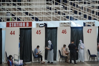 caption: Health staff and patients at an exhibition center in Kuala Lumpur that's been turned into Malaysia's first mega-vaccination center. The government aims to speed up inoculations amid a sharp spike in infections.