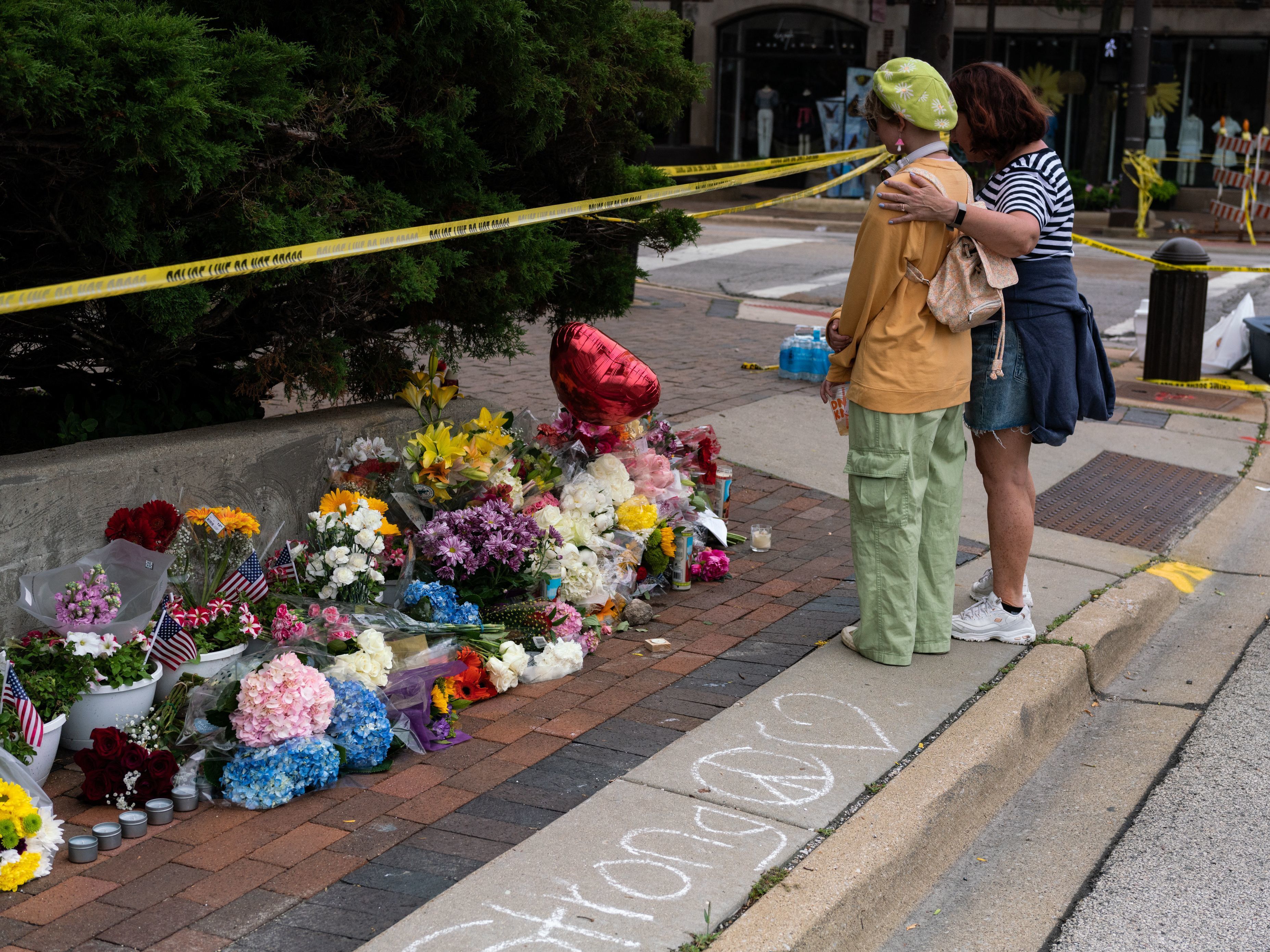 caption: Residents visit a makeshift memorial for victims of the 4th of July mass shooting in downtown Highland Park, Illinois on Wednesday.
