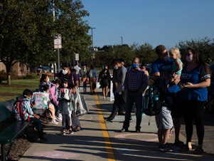 caption: Parents drop their children off for the first day of school in Novi, Mich., on Tuesday.