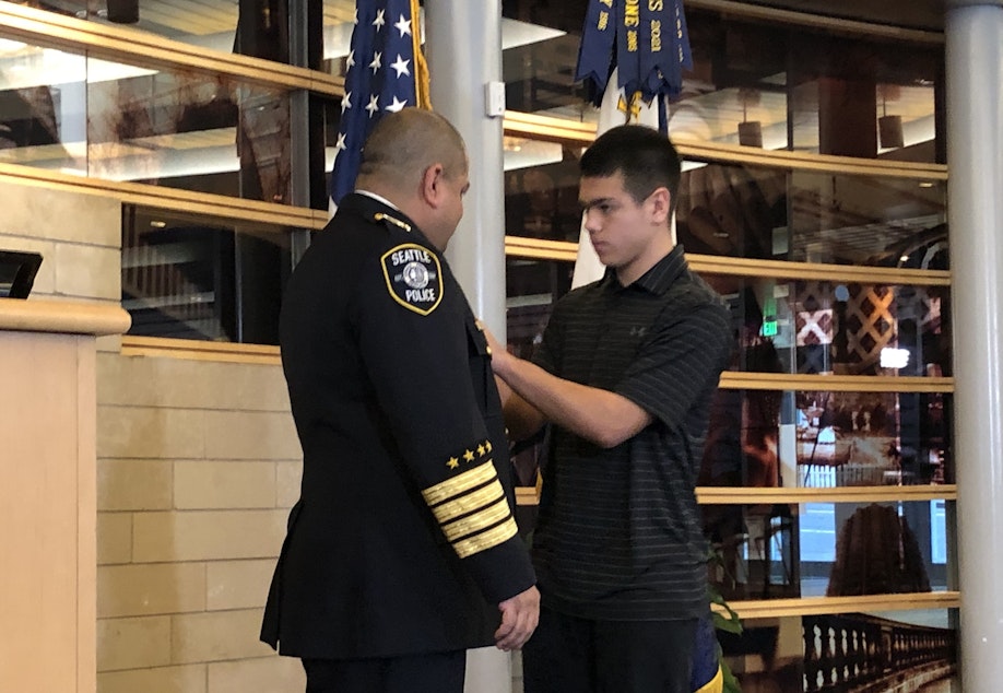 caption: Adrian Diaz was officially sworn in as Seattle's chief of police on Jan. 12, 2023, after two and a half years as interim chief. His son Alex pinned on his new badge in a ceremony at City Hall. 
