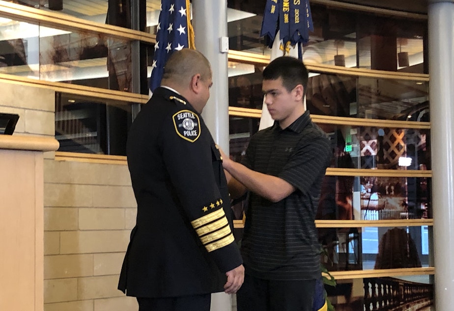 caption: Adrian Diaz was officially sworn in as Seattle's chief of police on Jan. 12, 2023, after two and a half years as interim chief. His son Alex pinned on his new badge in a ceremony at City Hall. 