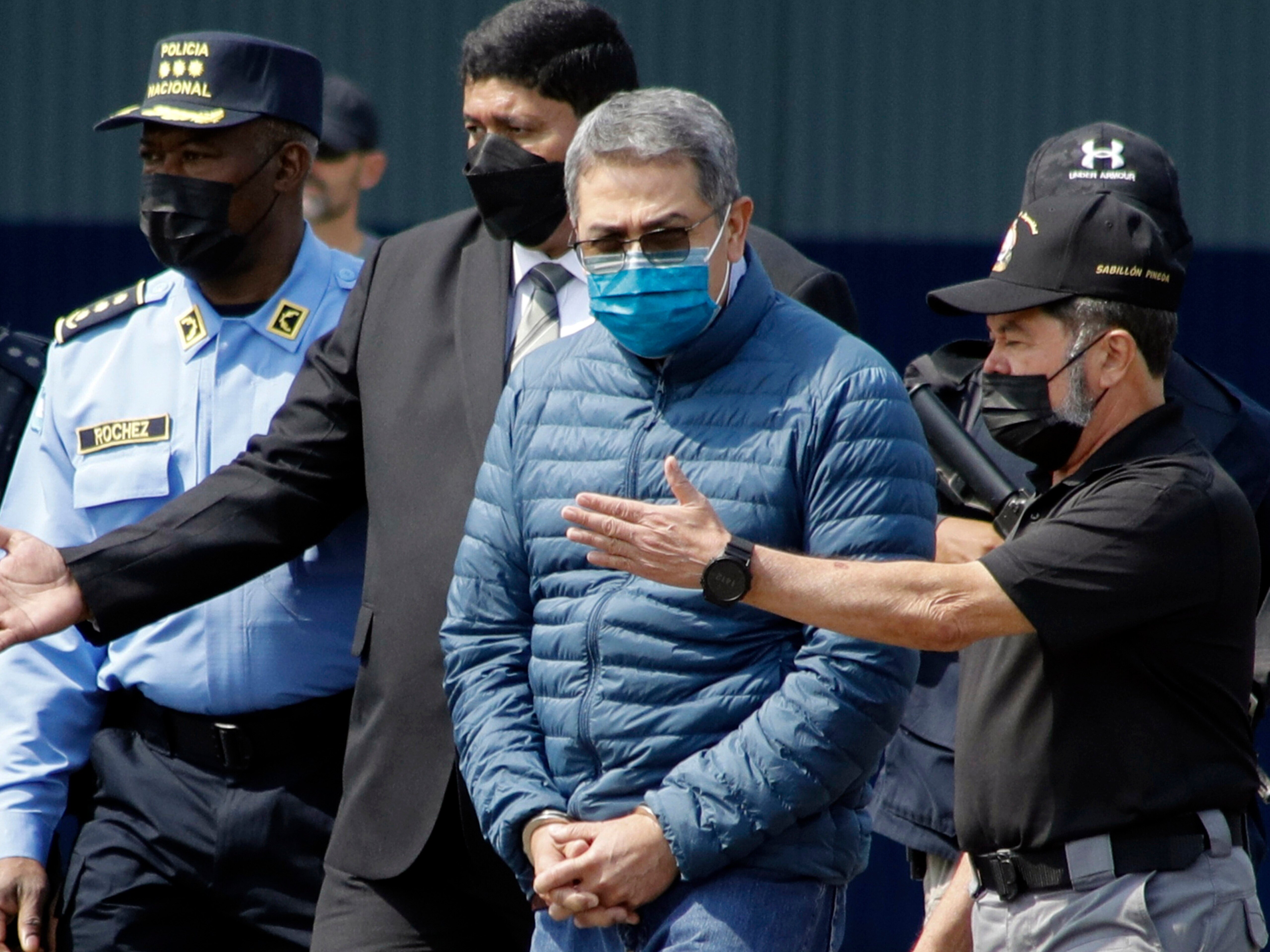 caption: Former Honduran President Juan Orlando Hernandez, second from right, is taken in handcuffs to a waiting aircraft as he is extradited to the United States, at an Air Force base in Tegucigalpa, Honduras, April 21, 2022.