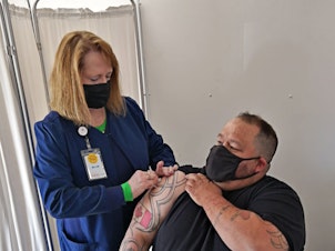 caption: John Harrower, a truck driver from the Canadian province of Manitoba, receives a COVID-19 vaccine shot in North Dakota in late April.