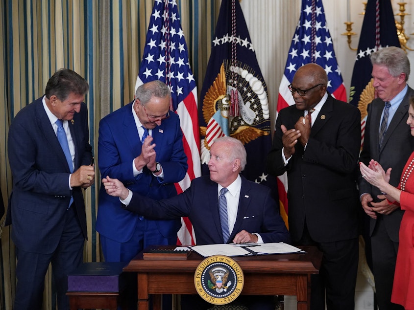 caption: President Biden hands a pen to Sen. Joe Manchin during the signing ceremony for the Inflation Reduction Act. Manchin was a key hold-out during negotiations, insisting on a smaller spending bill.