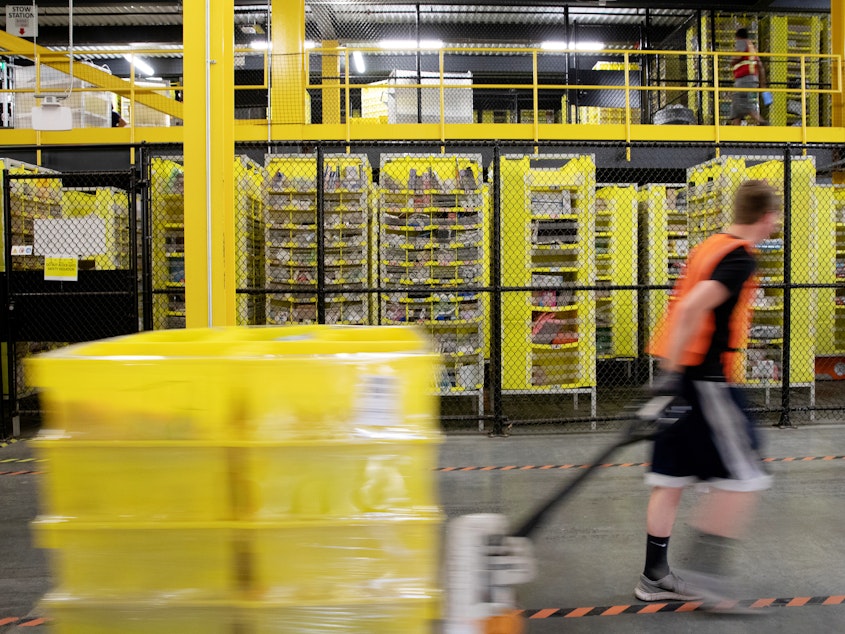 caption: A worker pulls a pallet jack with plastic crates at an Amazon warehouse in New Jersey. The company is facing its biggest labor battle yet with a unionization vote expected at a facility in Alabama.