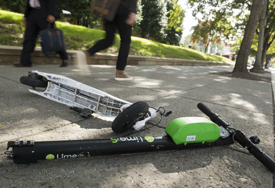 A broken Lime electric scooter lays on a sidewalk in Washington, D.C.