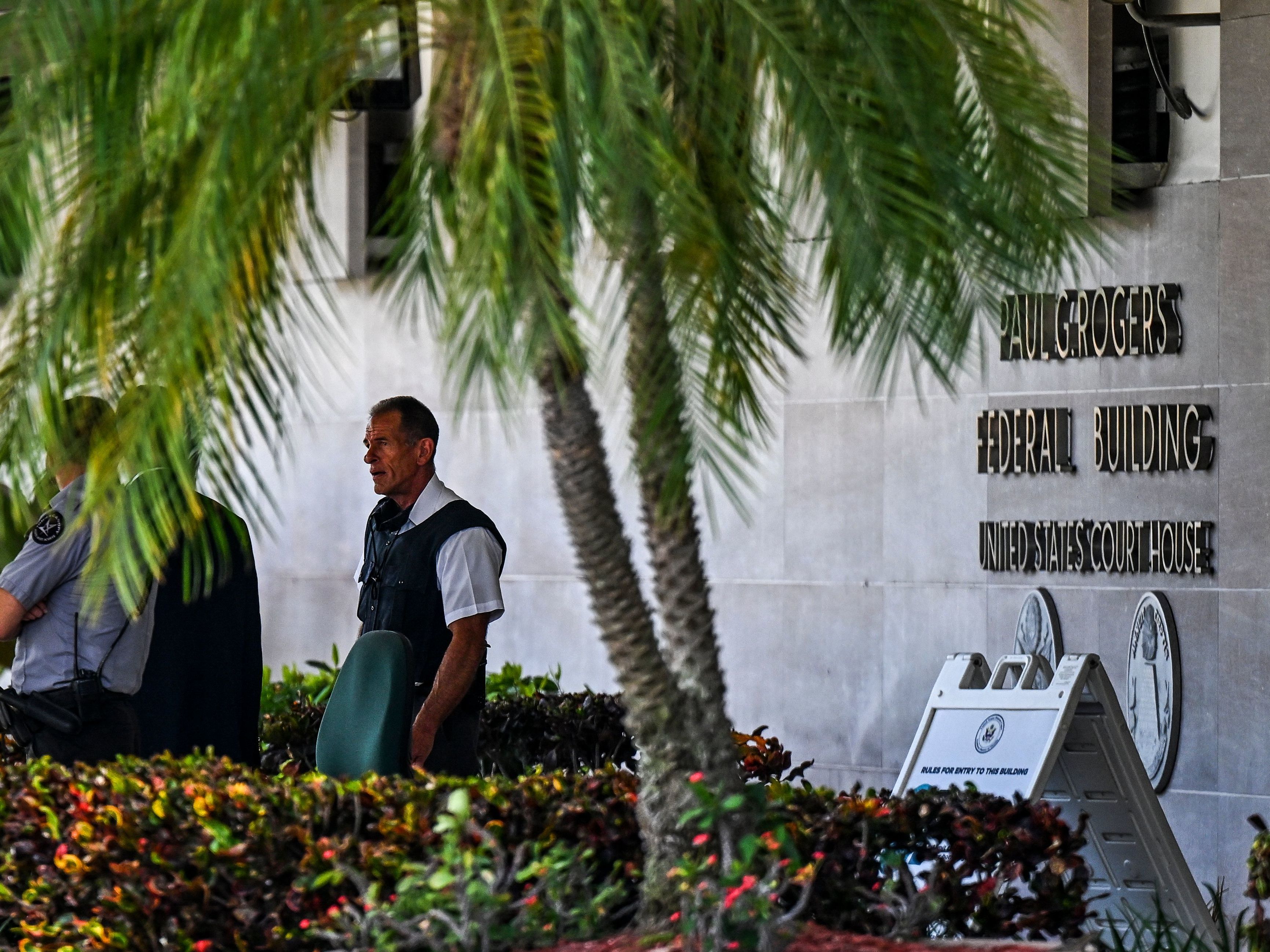 caption: Security officers guard the entrance to the Paul G. Rogers Federal Building & Courthouse as the court holds a hearing to determine if the affidavit used by the FBI as justification for last week's search of Trump's Mar-a-Lago estate should be unsealed, at the U.S. District Courthouse for the Southern District of Florida in West Palm Beach on Aug. 18.