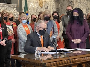 caption:  Gov. Jay Inslee prepares to sign gun-related legislation at a bill signing ceremony in the State Reception Room at the Capitol on Wednesday, March 23, 2022. One of the bills bans the manufacture and sale of gun magazines that hold more than 10 rounds of ammunition. 