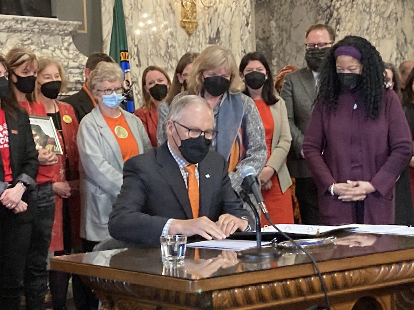 caption: Gov. Jay Inslee prepares to sign gun-related legislation at a bill signing ceremony in the State Reception Room at the Capitol on Wednesday, March 23, 2022. One of the bills bans the manufacture and sale of gun magazines that hold more than 10 rounds of ammunition.