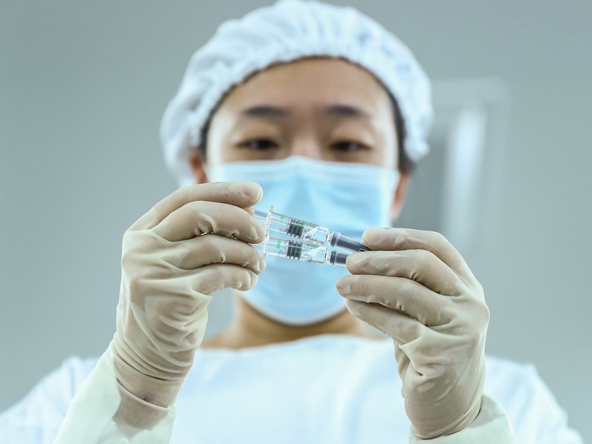 caption: A staff member checks a COVID-19 vaccine package in Beijing. China has approved Sinopharm's vaccine after clinical trials showed it has a 79% efficacy against COVID-19.