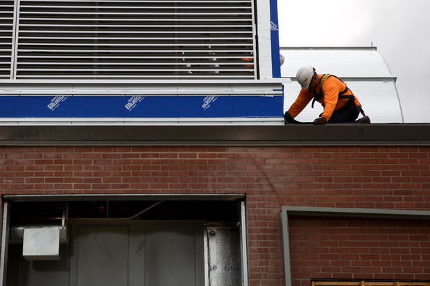 caption: <p>A construction worker works on the roof of Harriet Tubman Middle School.</p>