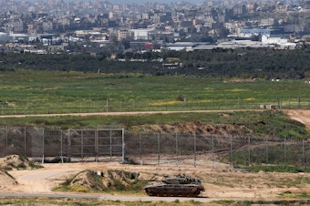 caption: This picture taken from Israel's southern border with the Gaza Strip shows an Israeli army tank moving along the border with the Palestinian territory on March 20.