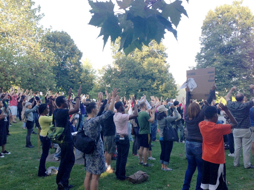 caption: Protesters hold their hands up at Pratt Park in Seattle's Central District for a Michael Brown rally.