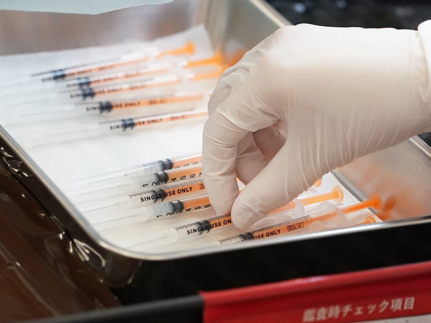 caption: A health care worker prepares the current COVID vaccine booster shots from Moderna in February. The company says a bivalent vaccine that combines the original strain with the omicron strain is the lead candidate for a fall vaccination campaign.