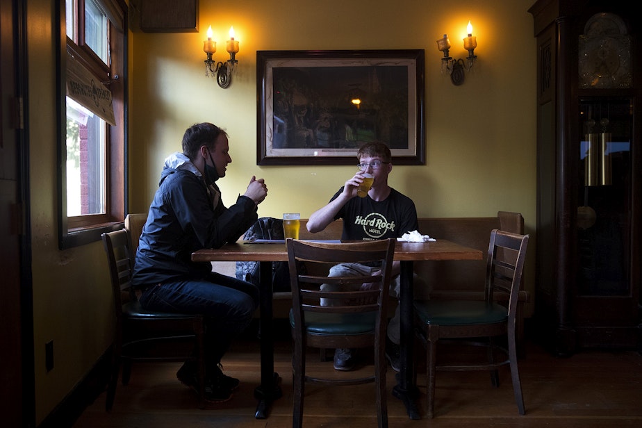 caption: Customers Tim Prusa, left, and Clayton Ness, right, drink beer on Friday, July 24, 2020, at the Tippe and Drague Alehouse on Beacon Avenue South in Seattle.