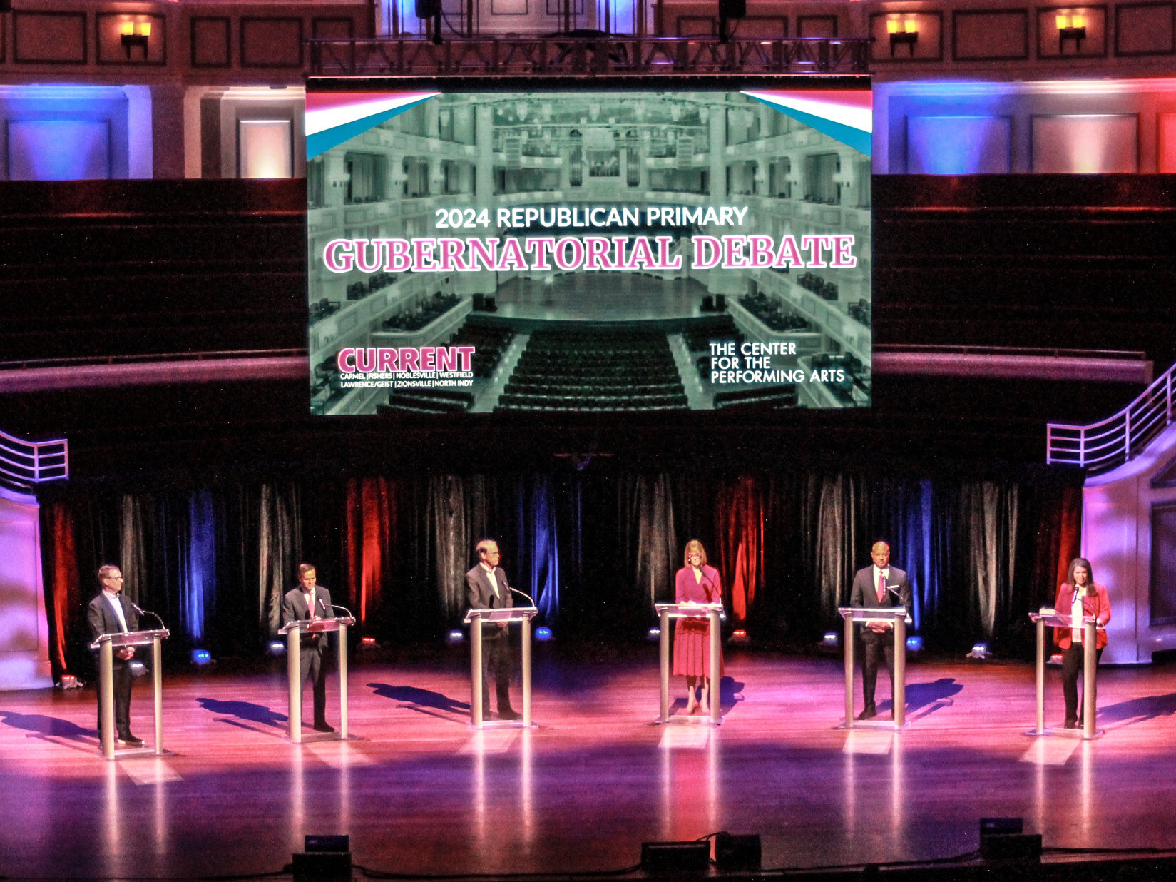 caption: GOP Indiana gubernatorial candidates Mike Braun, Brad Chambers, Suzanne Crouch, Eric Doden, Curtis Hill and Jamie Reitenour debate during a forum on March 11, 2024.