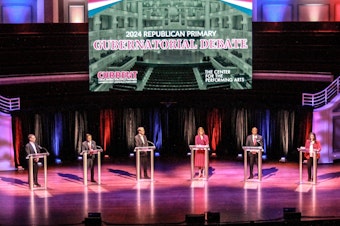 caption: GOP Indiana gubernatorial candidates Mike Braun, Brad Chambers, Suzanne Crouch, Eric Doden, Curtis Hill and Jamie Reitenour debate during a forum on March 11, 2024.