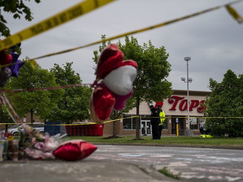 caption: People gather at the scene of a mass shooting at Tops Friendly Market at Jefferson Avenue and Riley Street on Monday, May 16, 2022 in Buffalo, NY.