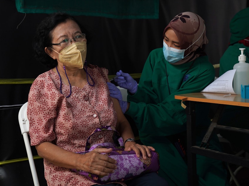 caption: A resident receives a dose of the Pfizer COVID-19 vaccine at a health center in Jakarta, Indonesia, on Jan. 13. This week, Indonesia started a program to give booster shots to the elderly and people at risk of severe disease.
