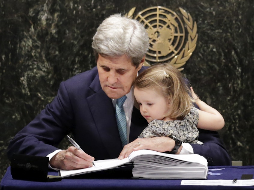 caption: Then-Secretary of State John Kerry holds his granddaughter Isabel Dobbs-Higginson as he signs the Paris Agreement on climate change in April 2016. Kerry has been chosen to serve as climate envoy in the incoming Biden administration.