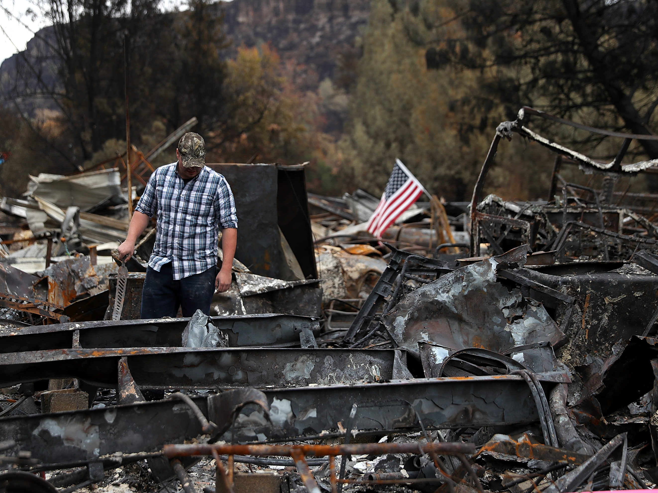 caption: Noah Fisher looks over his home that was destroyed by the Camp Fire in November 2018 in Paradise, California. Investigators are examining whether PG&E power lines helped ignite the fire.
