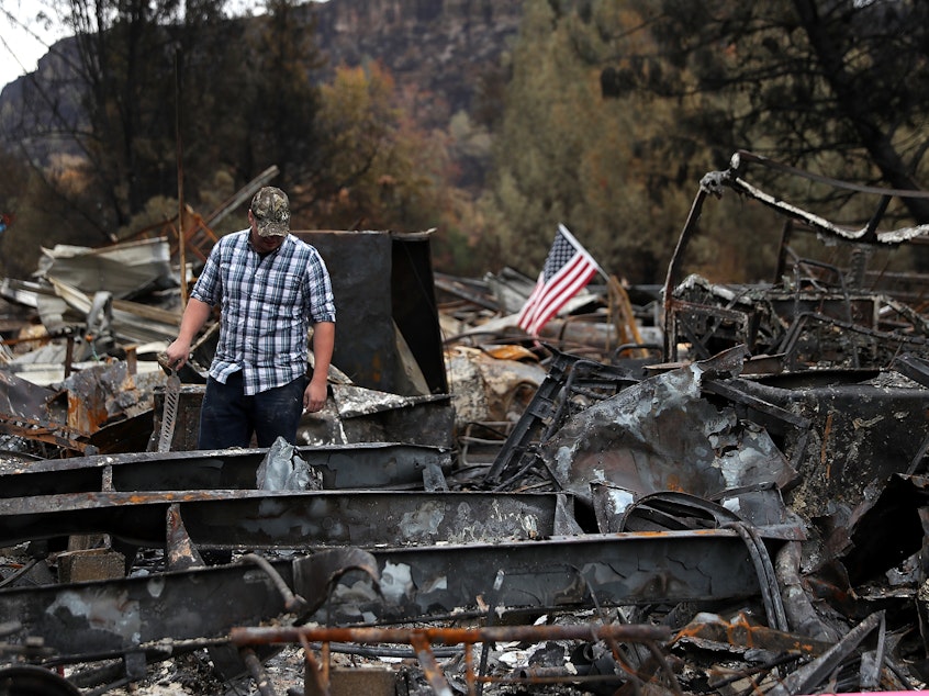 caption: Noah Fisher looks over his home that was destroyed by the Camp Fire in November 2018 in Paradise, California. Investigators are examining whether PG&E power lines helped ignite the fire.