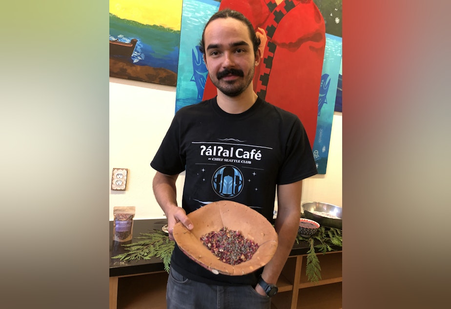 caption: Anthony Johnson (Anishnaabe) is manager and chef at ?al?al Café in Pioneer Square. The café is focused on Indigenous foods. Johnson is holding a bowl of midnight (herbal) tea from Oregon. 