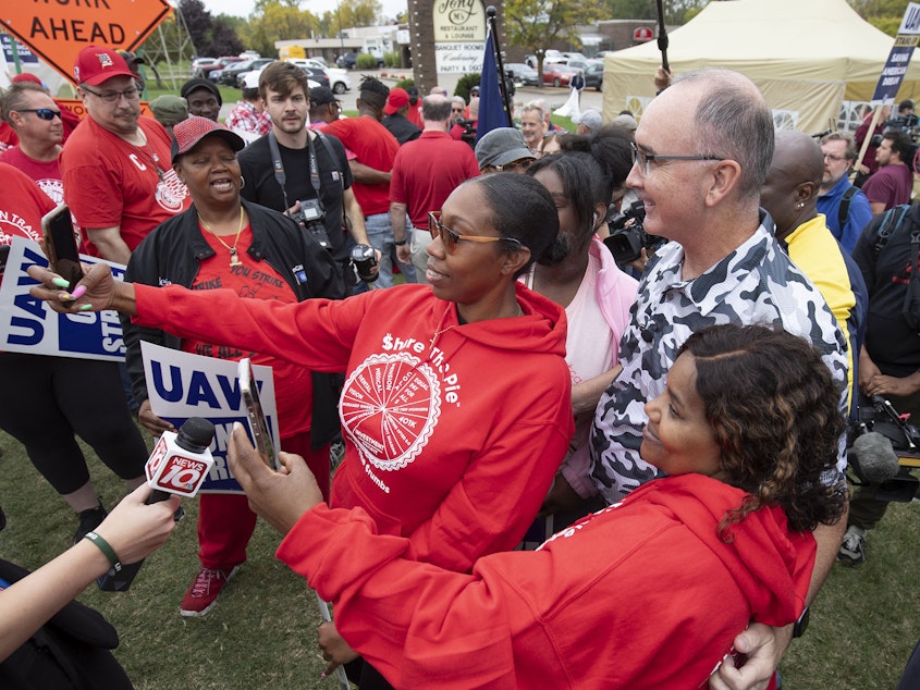 caption: United Auto Workers President Shawn Fain posed with UAW members as they strike the General Motors Lansing Delta Assembly Plant in Michigan in late September.