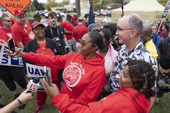 caption: United Auto Workers President Shawn Fain posed with UAW members as they strike the General Motors Lansing Delta Assembly Plant in Michigan in late September.