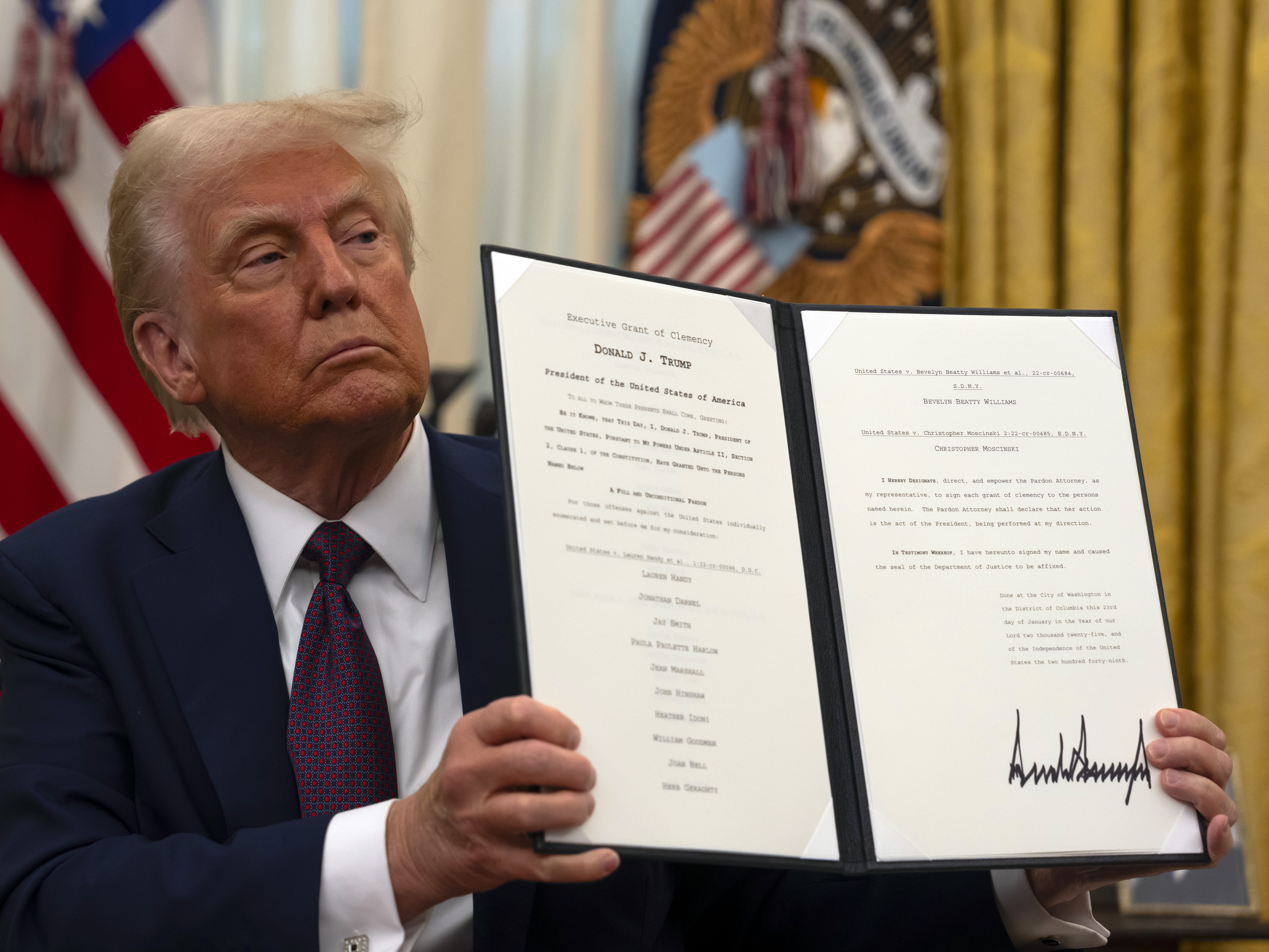 caption: President Trump holds up a signed executive order relating to clemency for anti-abortion protesters in the Oval Office in January.