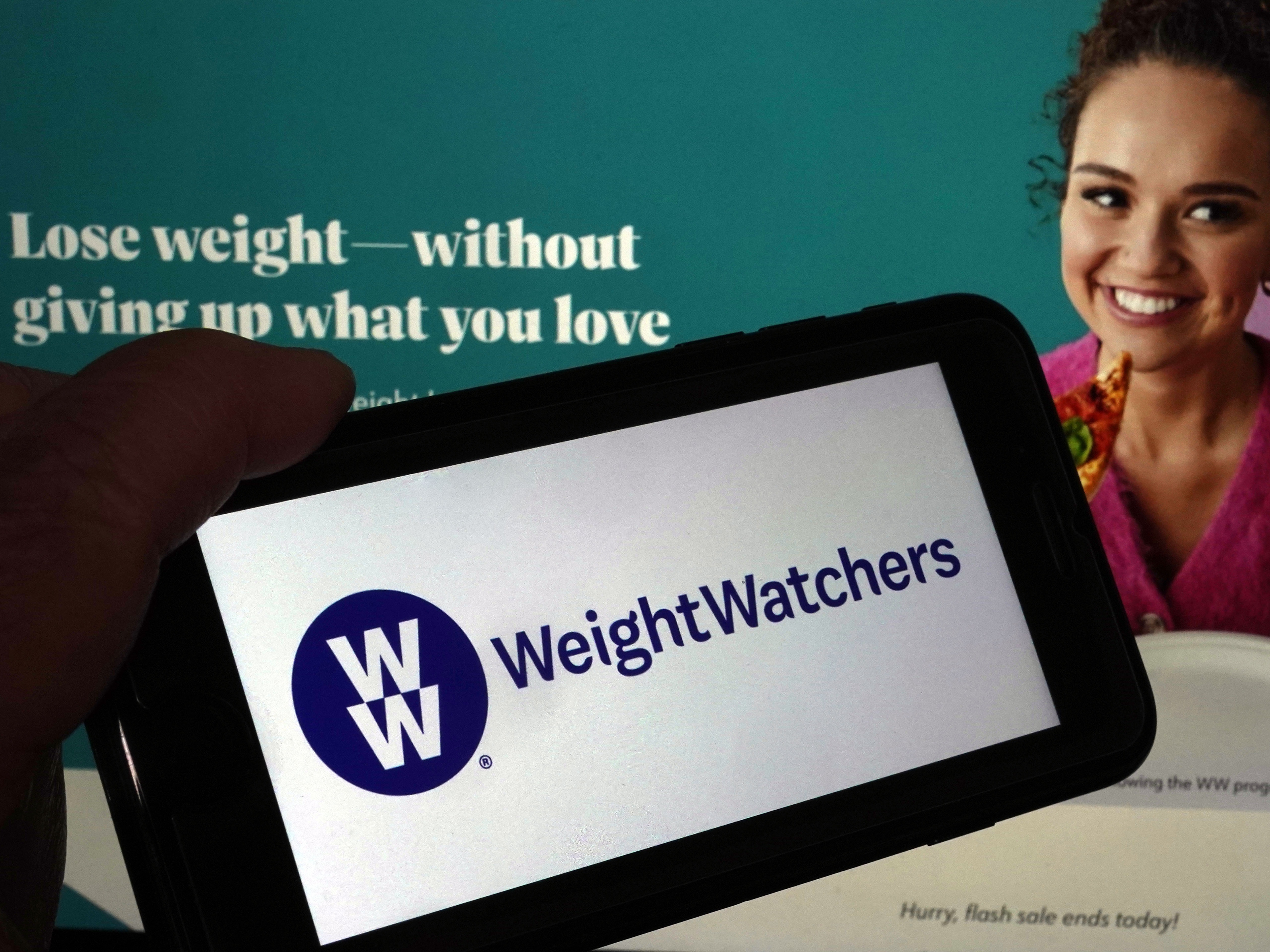 caption: This image shows the logo of WeightWatchers on a mobile phone, and the company's website, in New York, March 7, 2023.