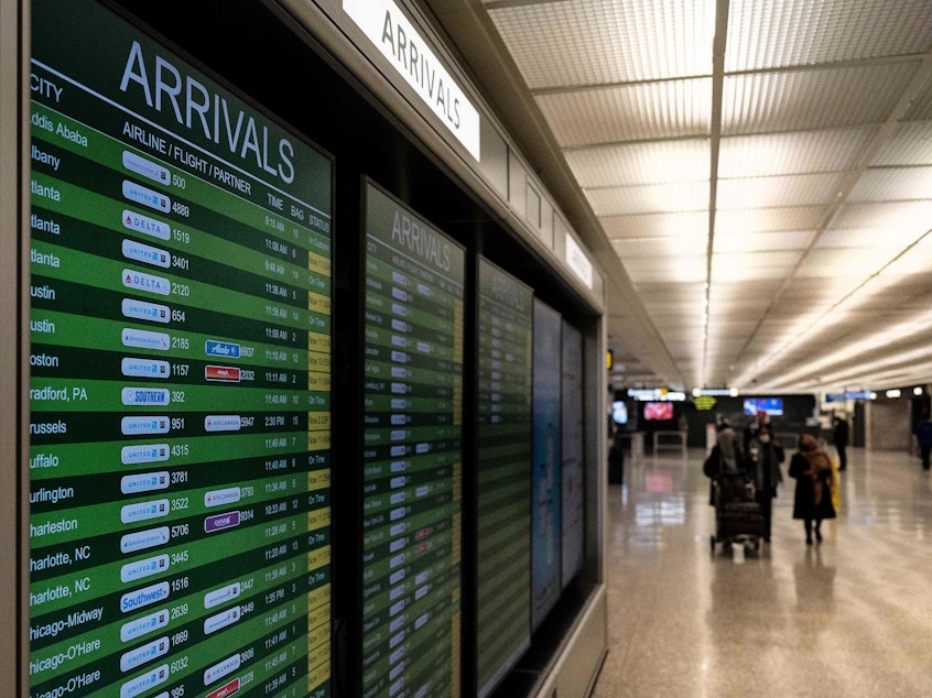 caption: Travelers exit the International Arrivals area at Dulles International Airport in Dulles, Virginia, on Monday. The Biden administration is banning travel for non-U.S. citizens from several African countries over concerns about the omicron variant.