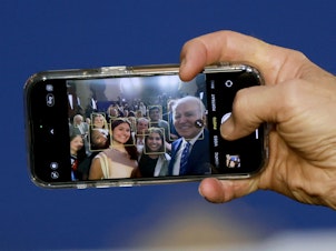 caption: President Biden takes a selfie using a guest's phone during an event at the University of Tampa on Feb. 9, 2023.