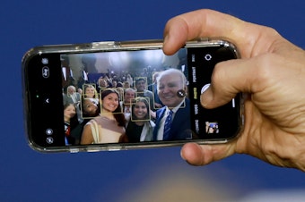 caption: President Biden takes a selfie using a guest's phone during an event at the University of Tampa on Feb. 9, 2023.