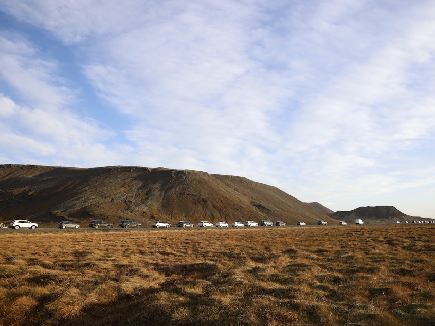 caption: A line of cars queued on a road heading to the town of Grindavik, Iceland, Monday.