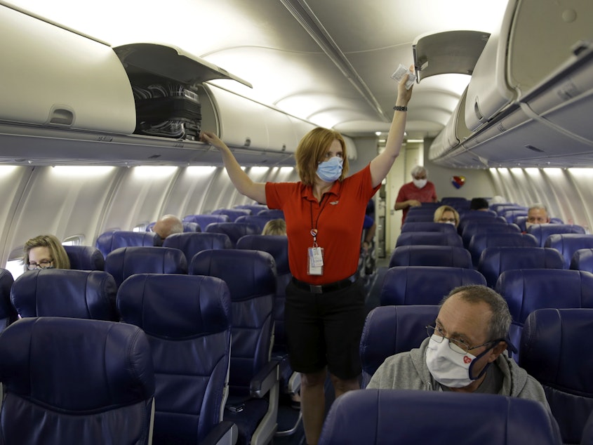 caption: In this 2020 file photo, a Southwest Airlines flight attendant prepares a plane bound for takeoff at the Kansas City International airport in Kansas City, Mo.