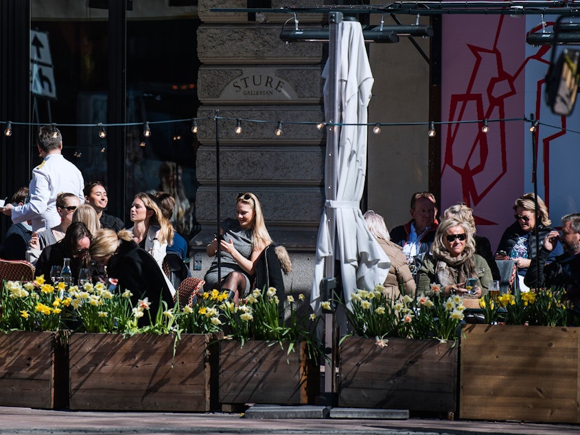 caption: People enjoy the spring weather as they sit at a restaurant in Stockholm on April 15 during the coronavirus pandemic.