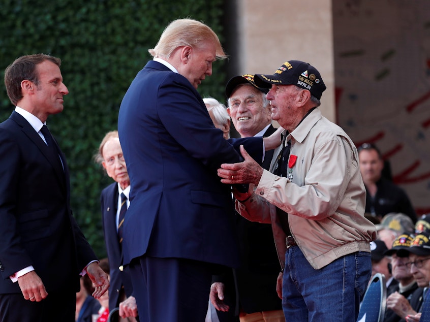 caption: President Trump and French President Emmanuel Macron greet a U.S. veteran during the commemoration marking the 75th anniversary of the Allied landings on D-Day at the Normandy American Cemetery and Memorial in Colleville-sur-Mer, France.