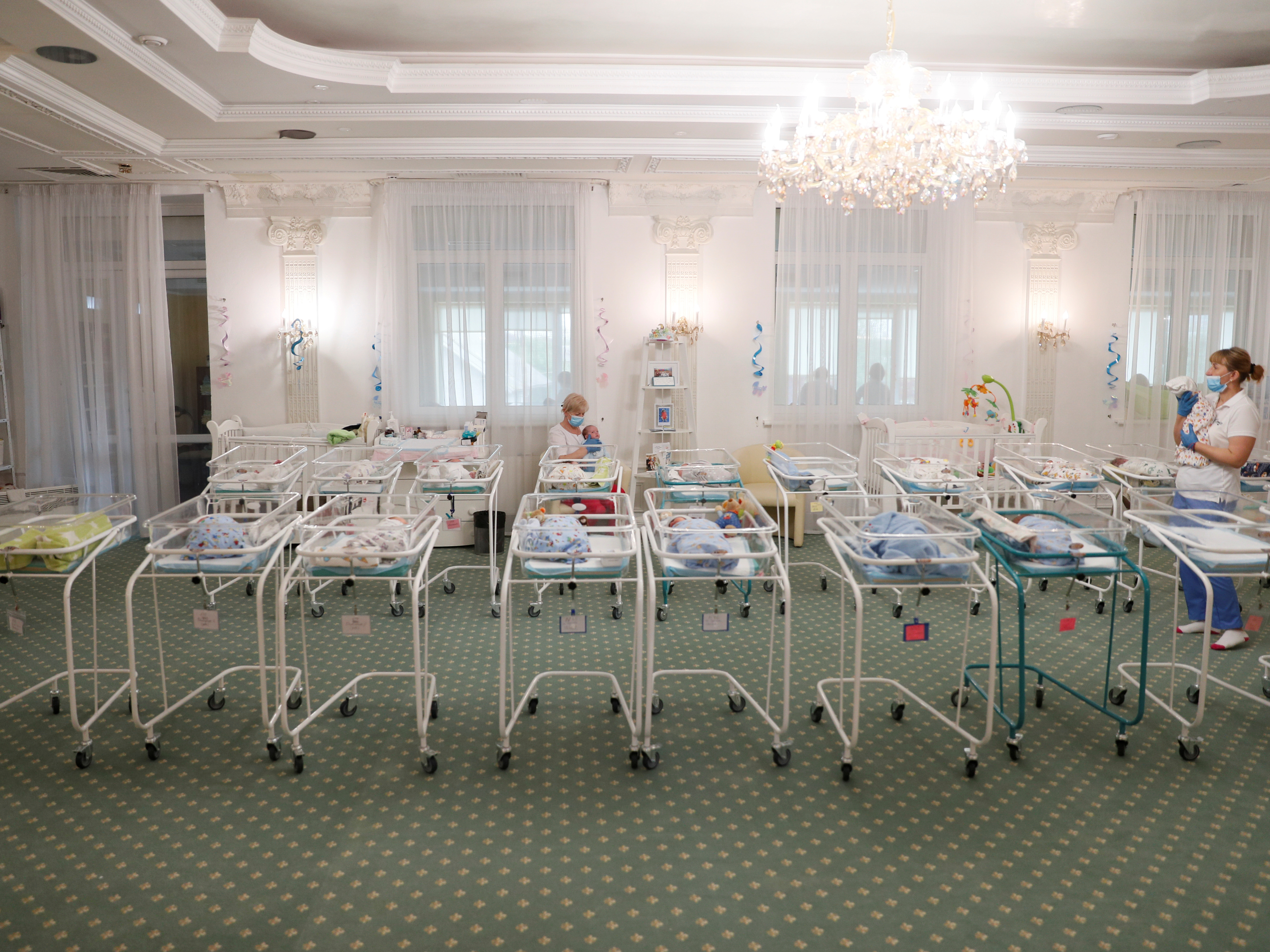 caption: Nurses and newborns in Hotel Venice, a facility owned by BioTexCom clinic in Kyiv, Ukraine, on Thursday. Dozens of babies born to surrogate mothers are stranded in Ukraine as the coronavirus restrictions prevent  foreign parents from collecting them.