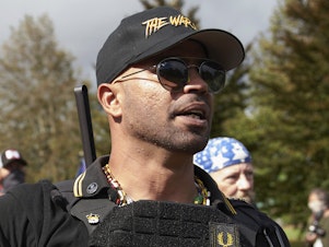 caption: Proud Boys leader Enrique Tarrio speaks at a rally in Delta Park on Sept. 26, 2020, in Portland, Ore.