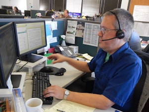 caption: Alex Williams, an operator for 211, King County's information line for emergency food or shelter.