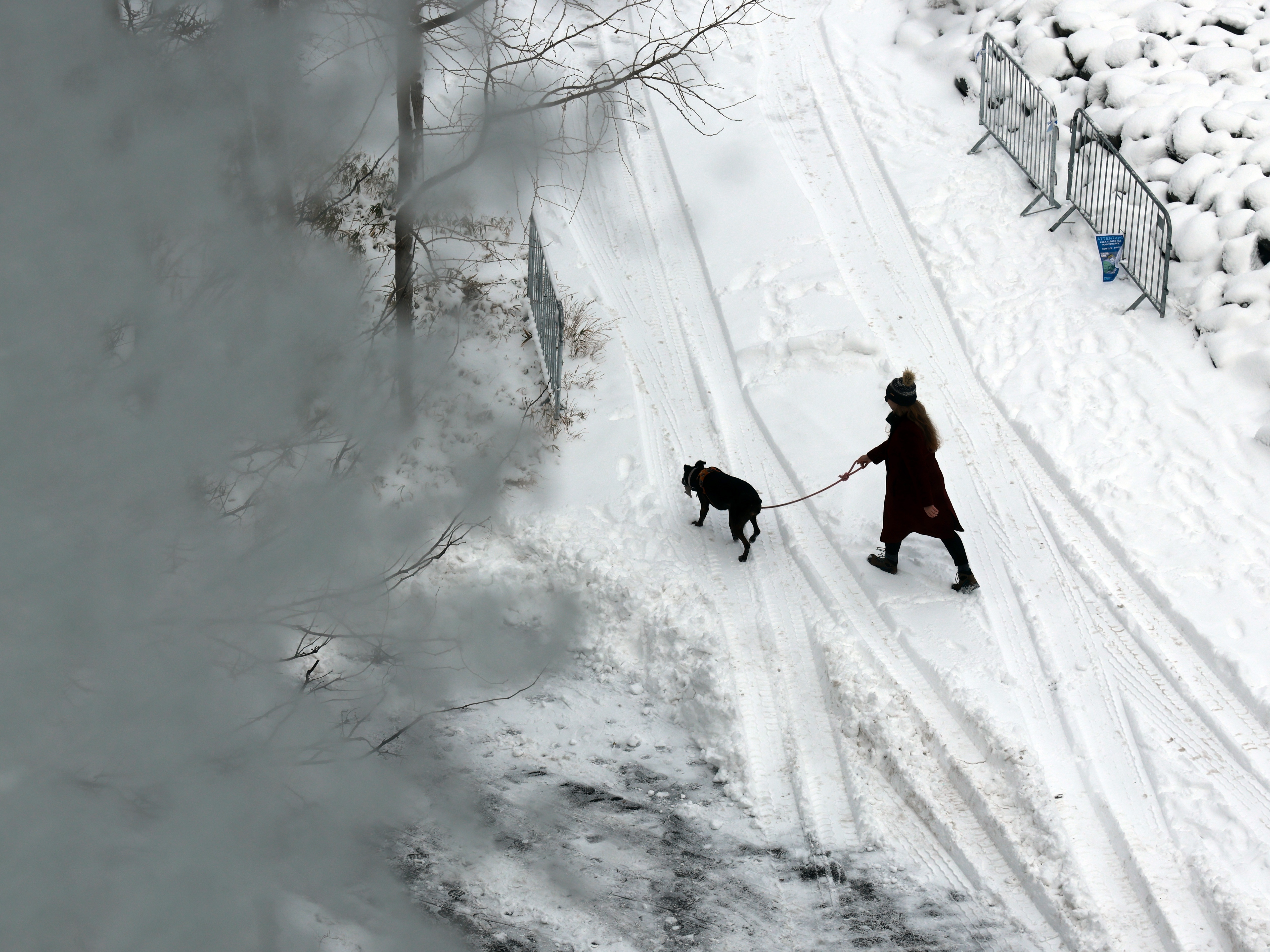 caption: People walk through the snow in Brooklyn after an overnight storm on Saturday in New York City.