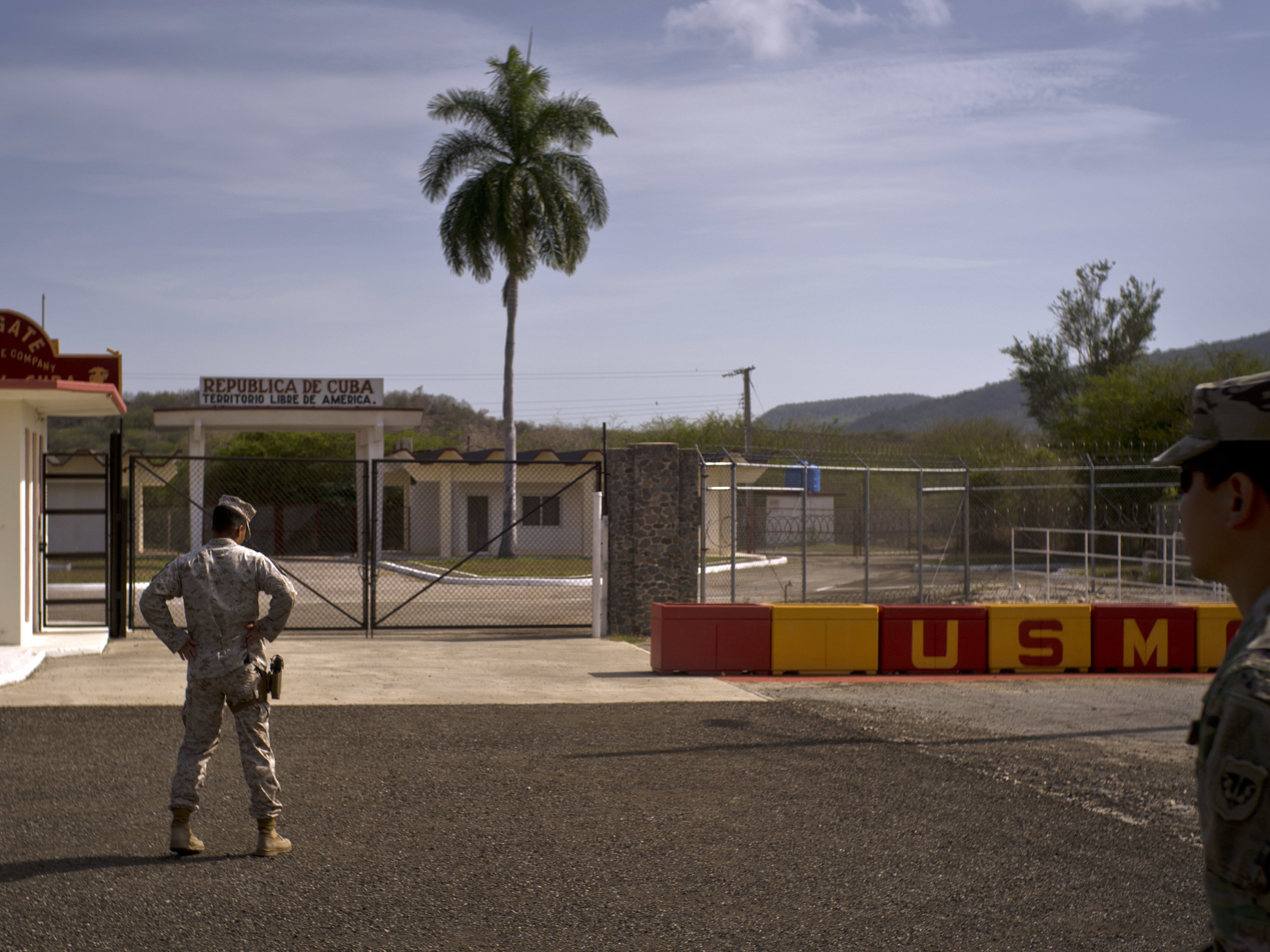 caption: In this photo reviewed by U.S. military officials, an Army soldier, right, and a Marine stand in front of the gates that separate the Cuban side from the Guantanamo Bay U.S. Naval Base, June 6, 2018.