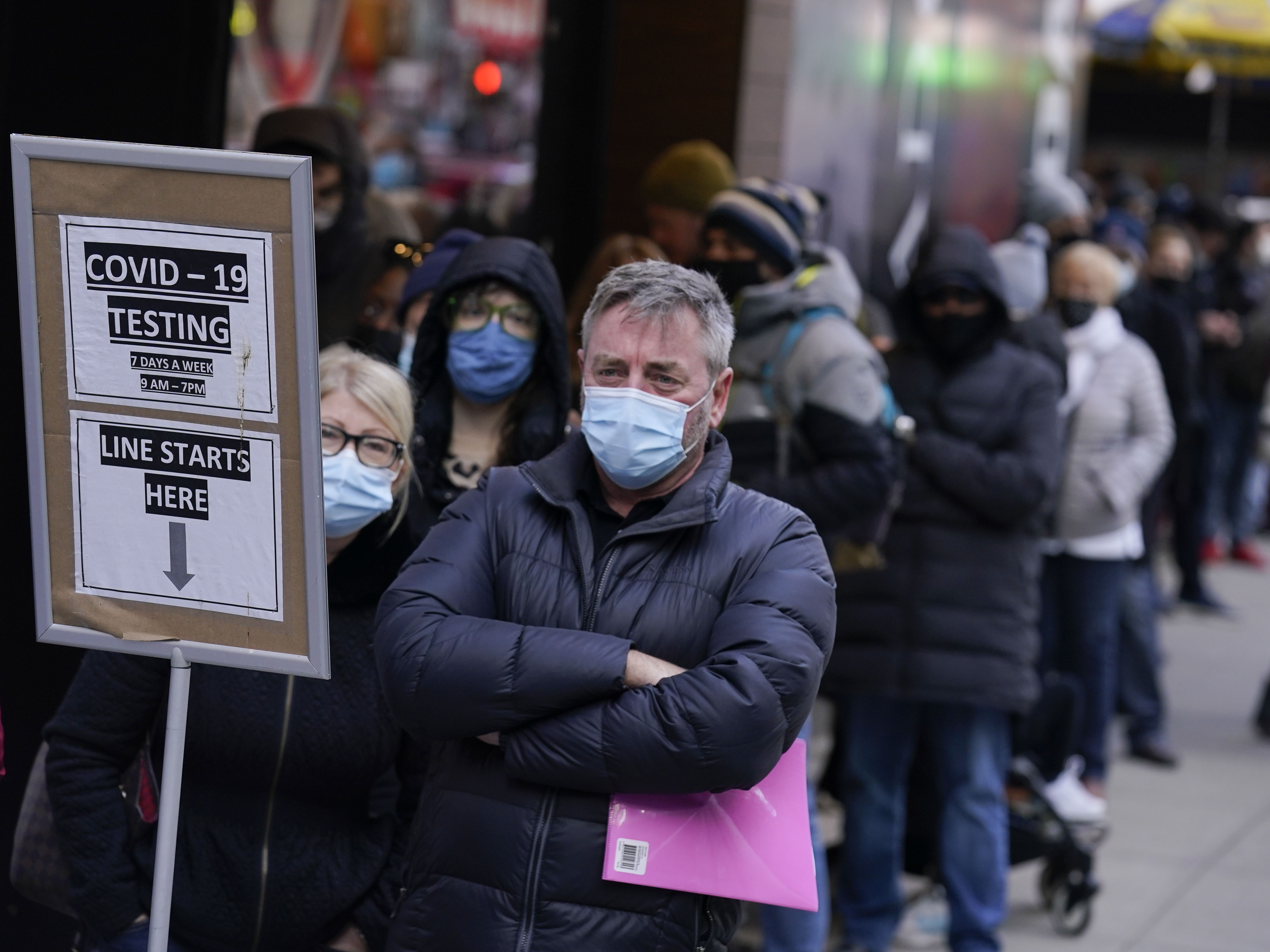caption: People wait in line at a COVID-19 testing site in Times Square, New York, Monday, Dec. 13, 2021.