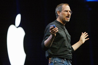 caption: Steve Jobs, then CEO of Apple, delivers the keynote address at the Worldwide Developers Conference in 2003 in San Francisco. Jobs created a personal uniform for himself that featured a black turtleneck from Japanese designer Issey Miyake.