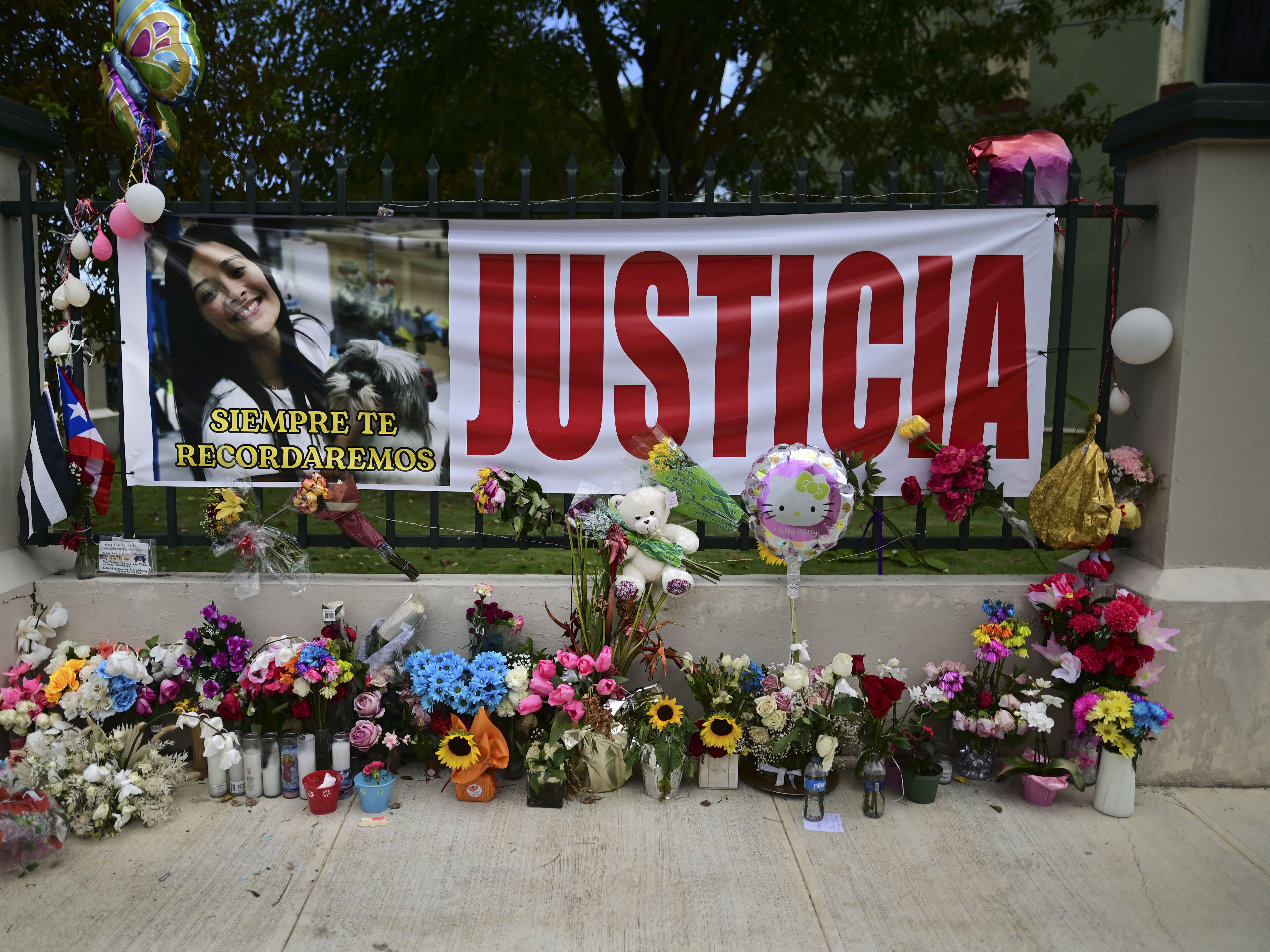 caption: Flowers, balloons and a poster with the Spanish word for "justice" is part of a growing makeshift memorial for Keishla Rodriguez whose lifeless body was found in a lagoon Saturday, at the entrance of where she lived in San Juan, Puerto Rico.