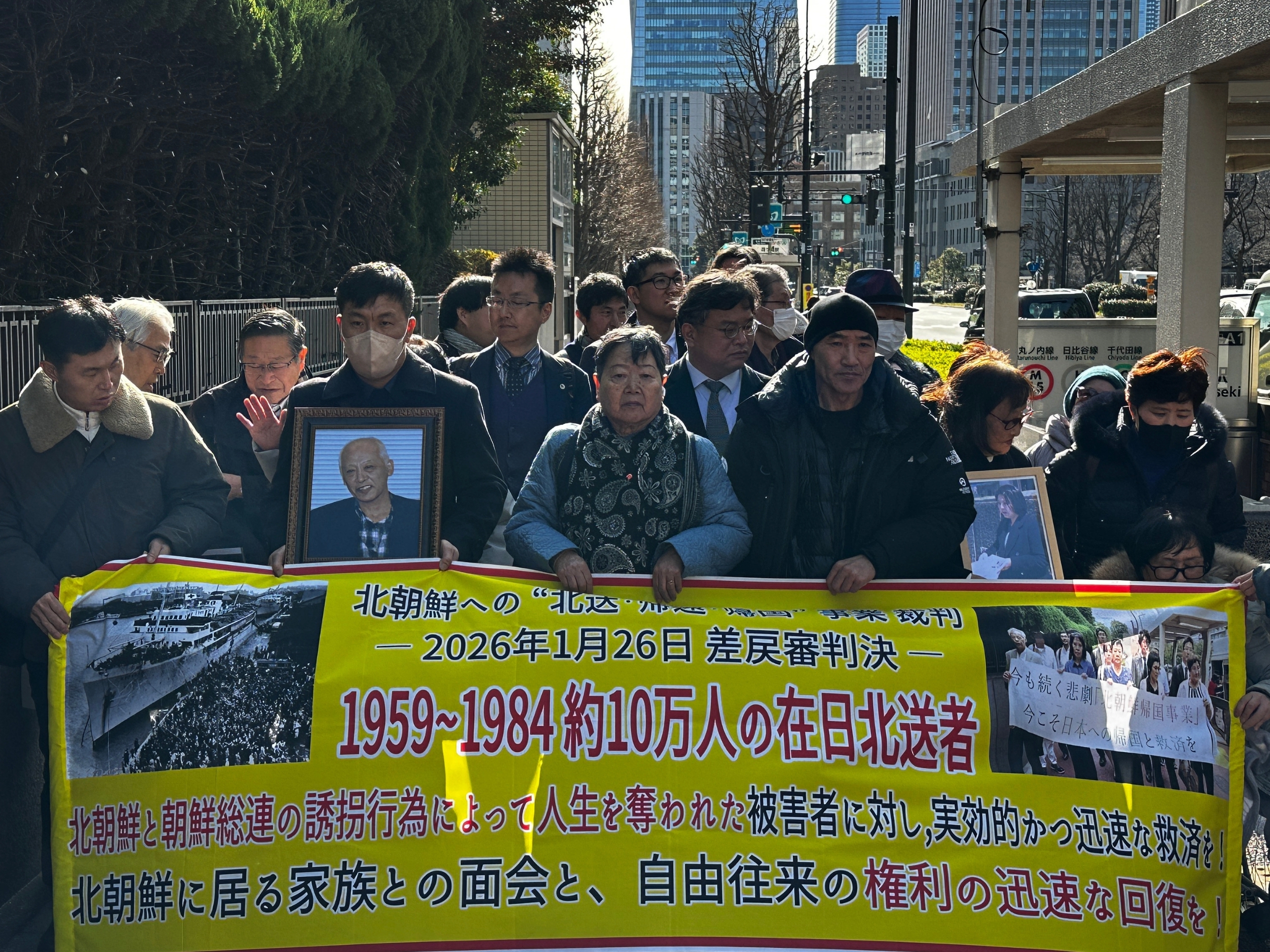 caption: Plaintiffs, supporters and lawyers in a lawsuit against the North Korean government march to Tokyo District Court on Jan. 26 to hear the verdict, holding a banner detailing their case.