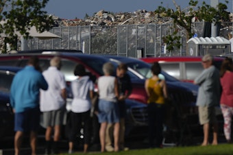 caption: A pile of debris from Hurricane Ian rises behind a line of people waiting to vote in Fort Myers, Fla., in November 2022. Research suggests support for some climate policies increases immediately after climate-driven disasters such as Ian.