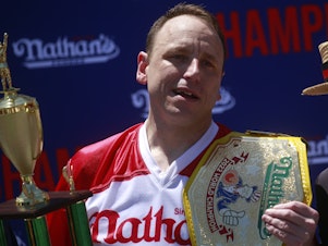 caption: Joey Chestnut emerges victorious after eating 63 hot dogs in 10 minutes during the 2022 Nathans Famous Fourth of July International Hot Dog Eating Contest in New York City.
